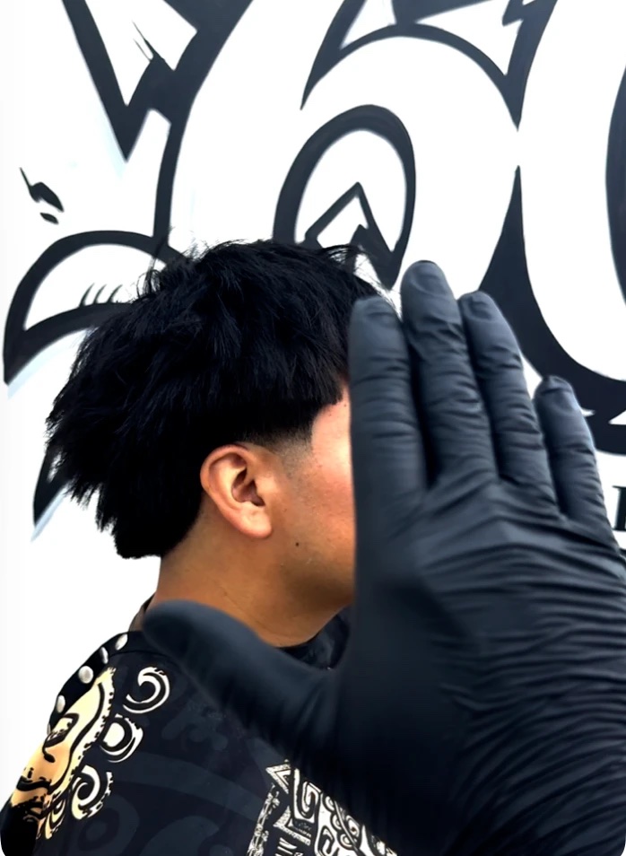 Side view of a taper with a spiky textured top in front of a graffiti mural